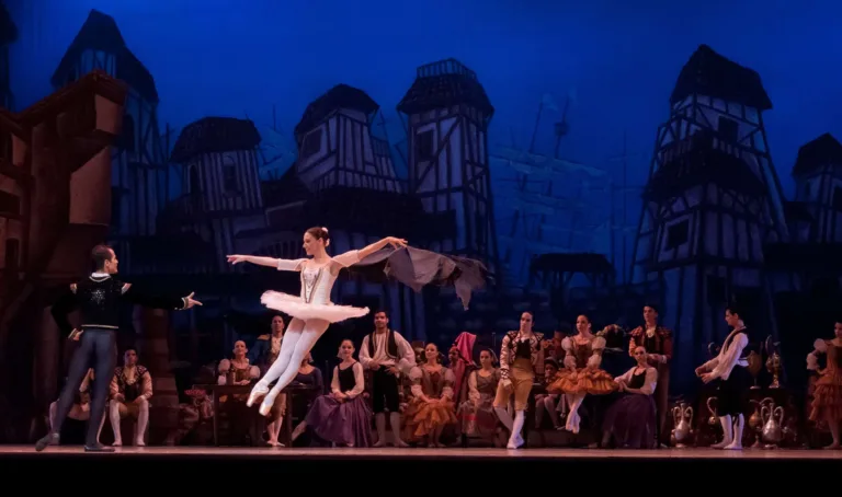 A ballerina on stage making a jump and hanging in the air