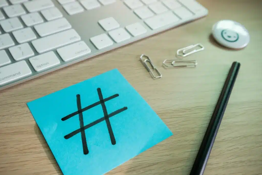 a post-it with a hashtag sign on it on a table next to staples, keyboard and a pen